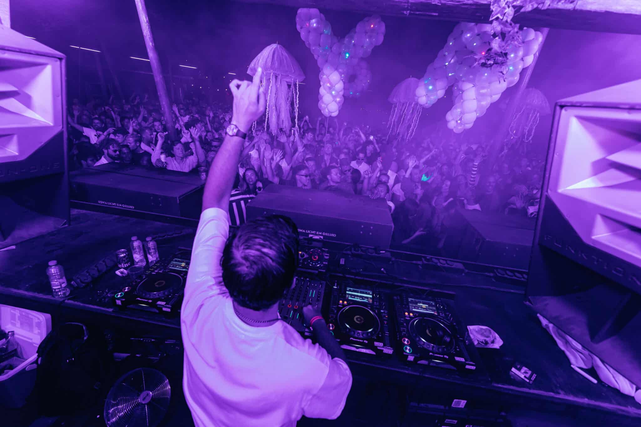 DJ Colyn behind the decks with Spellbound balloon letters and jellyfish Floaters above the crowd in purple light at Thuishaven Amsterdam — Out of Thin Air — Photo by Rachel Ecclestone