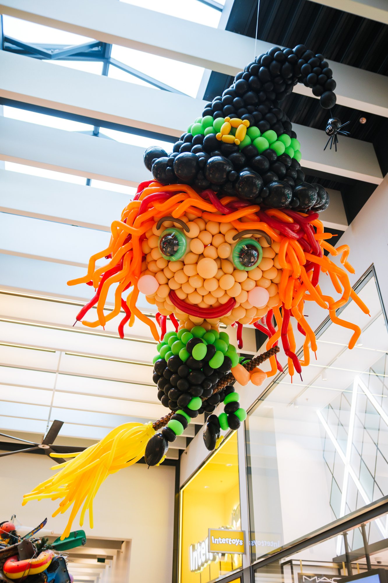 Balloon witch on a broomstick under the roof of Gelderlandplein (2026) — Design: Birgit Bourgonje — Photo: zestien:negen